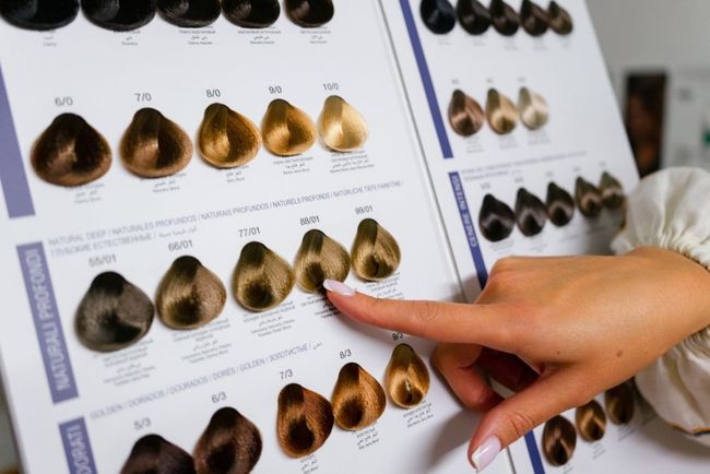 A woman is pointing at a chart of hair colors.