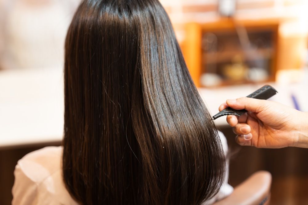 A woman is getting her hair done by a hairdresser in a salon.