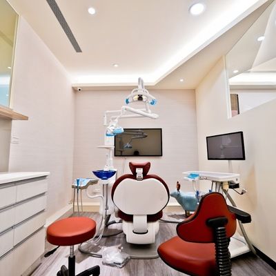 A dental office with a red chair and a white chair