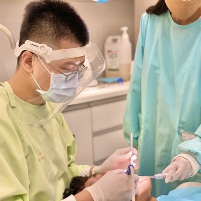 A dentist is examining a patient 's teeth in a dental office.