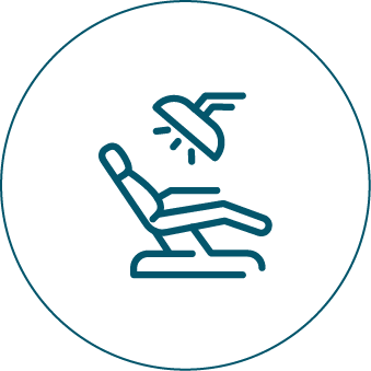 A person is sitting in a dental chair with a light on their head.