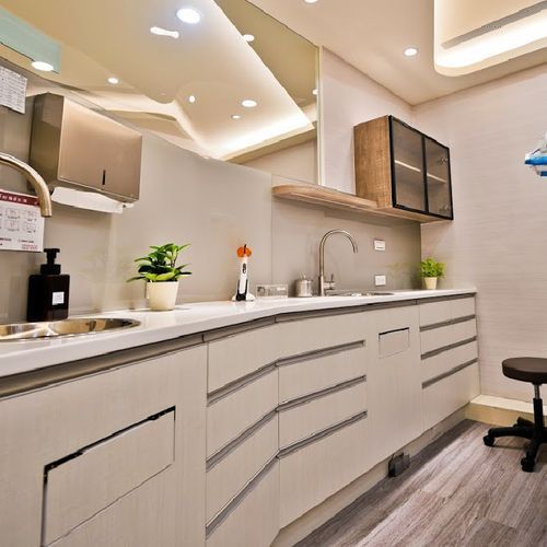A kitchen with white cabinets , a sink , and a stool.