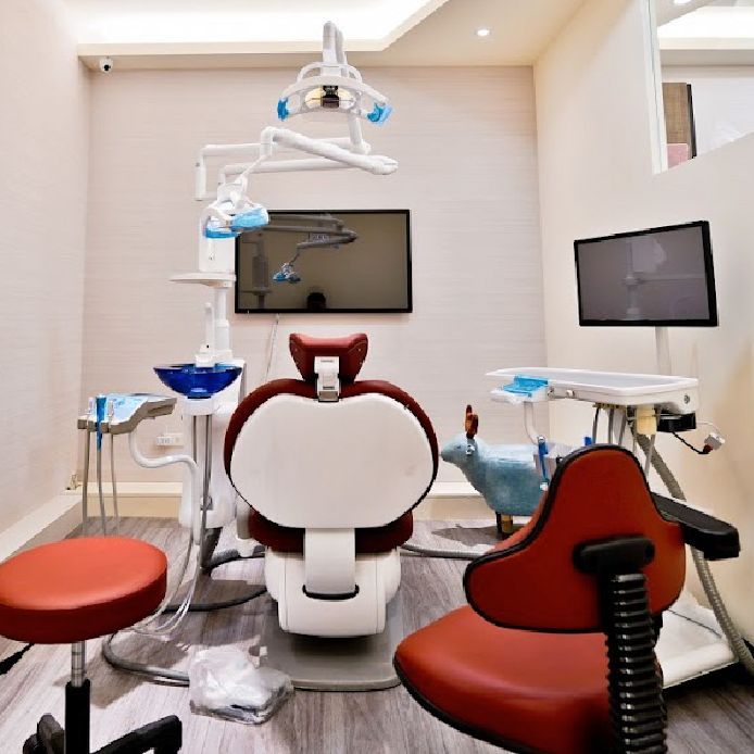 A dental office with a red chair and a white chair