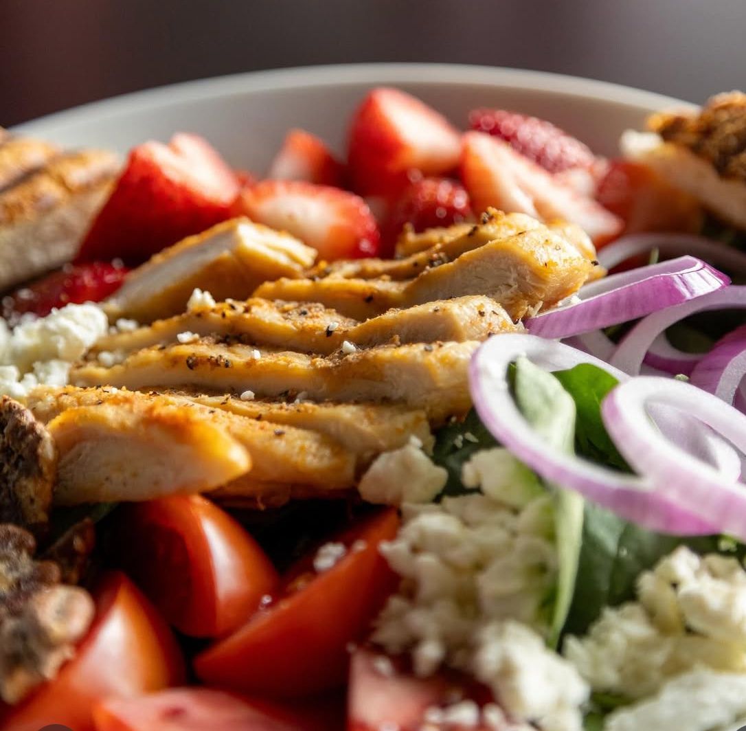 Croissant breakfast sandwich with sausage and egg, cut in half on a white plate on a wooden surface.