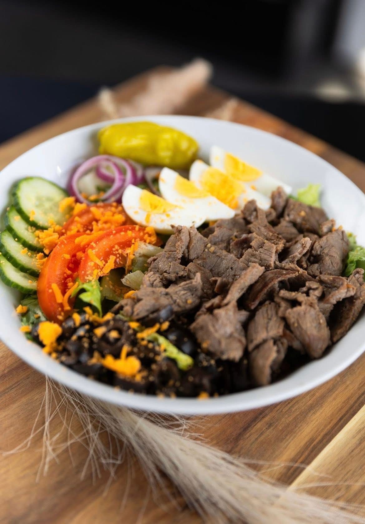 Breakfast sandwich cut in half on a white plate, showcasing egg, sausage, and croissant.
