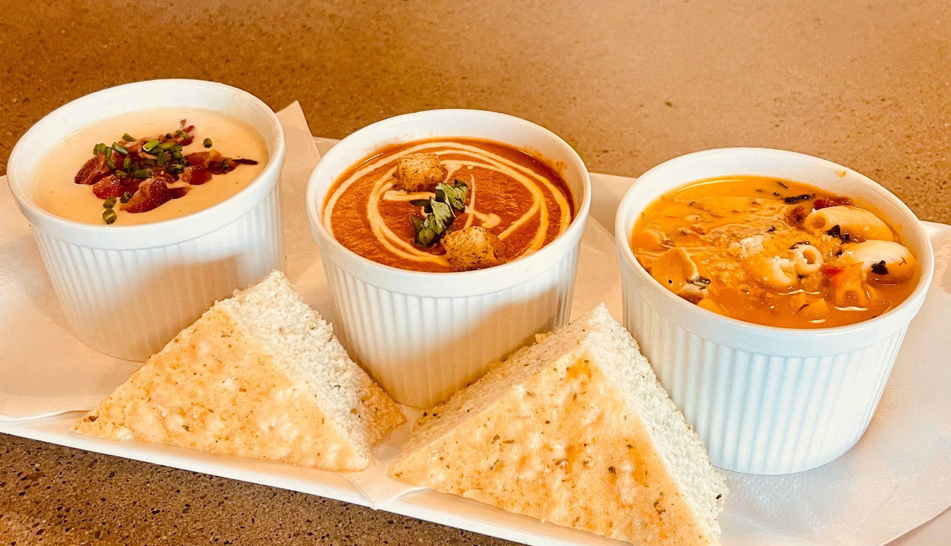 Cheesesteak sandwich with side of potato salad, pickles, and dipping sauce.