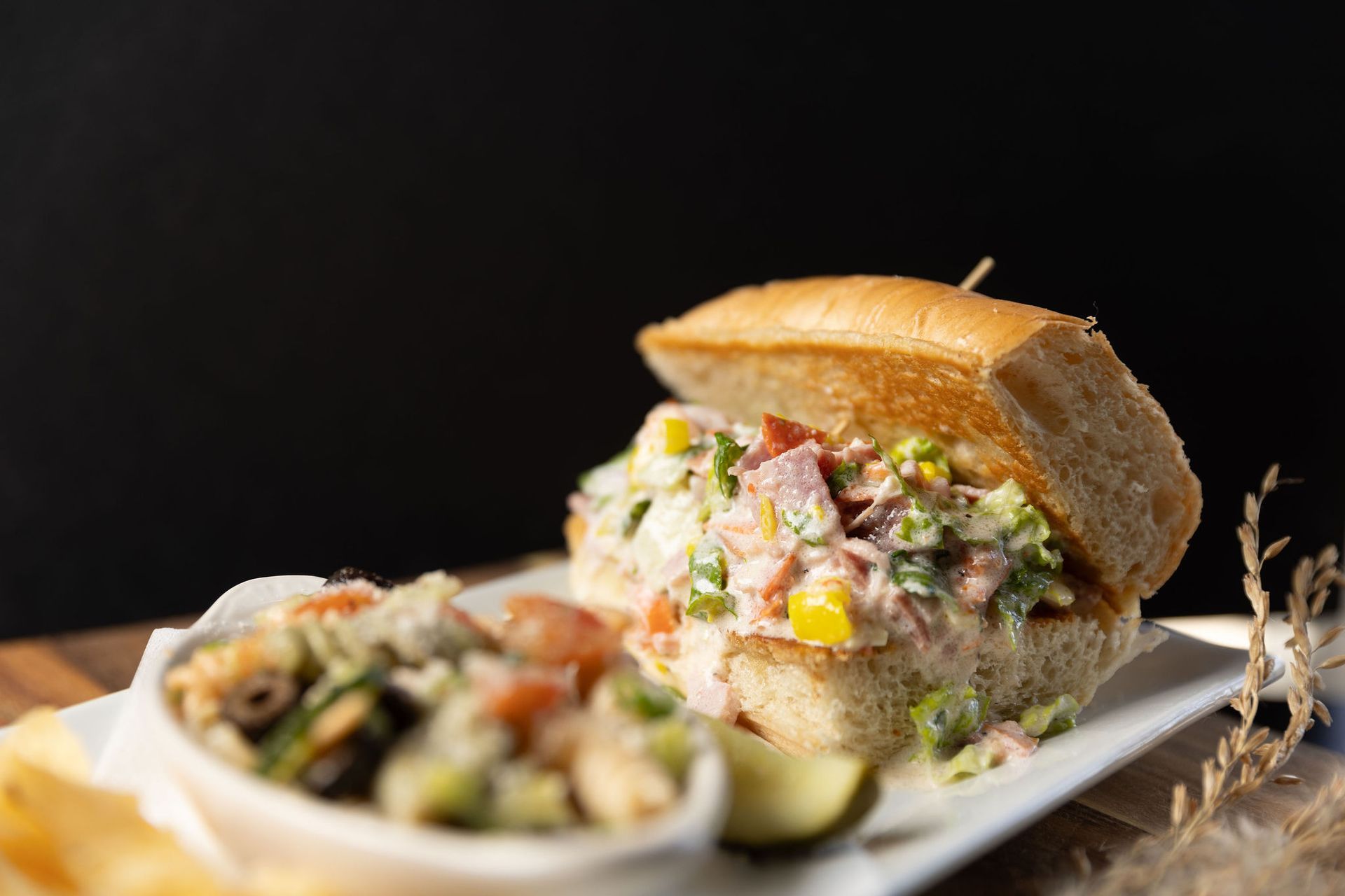 Sandwich with a creamy filling, small dish of mussels, on a white plate. Black background.