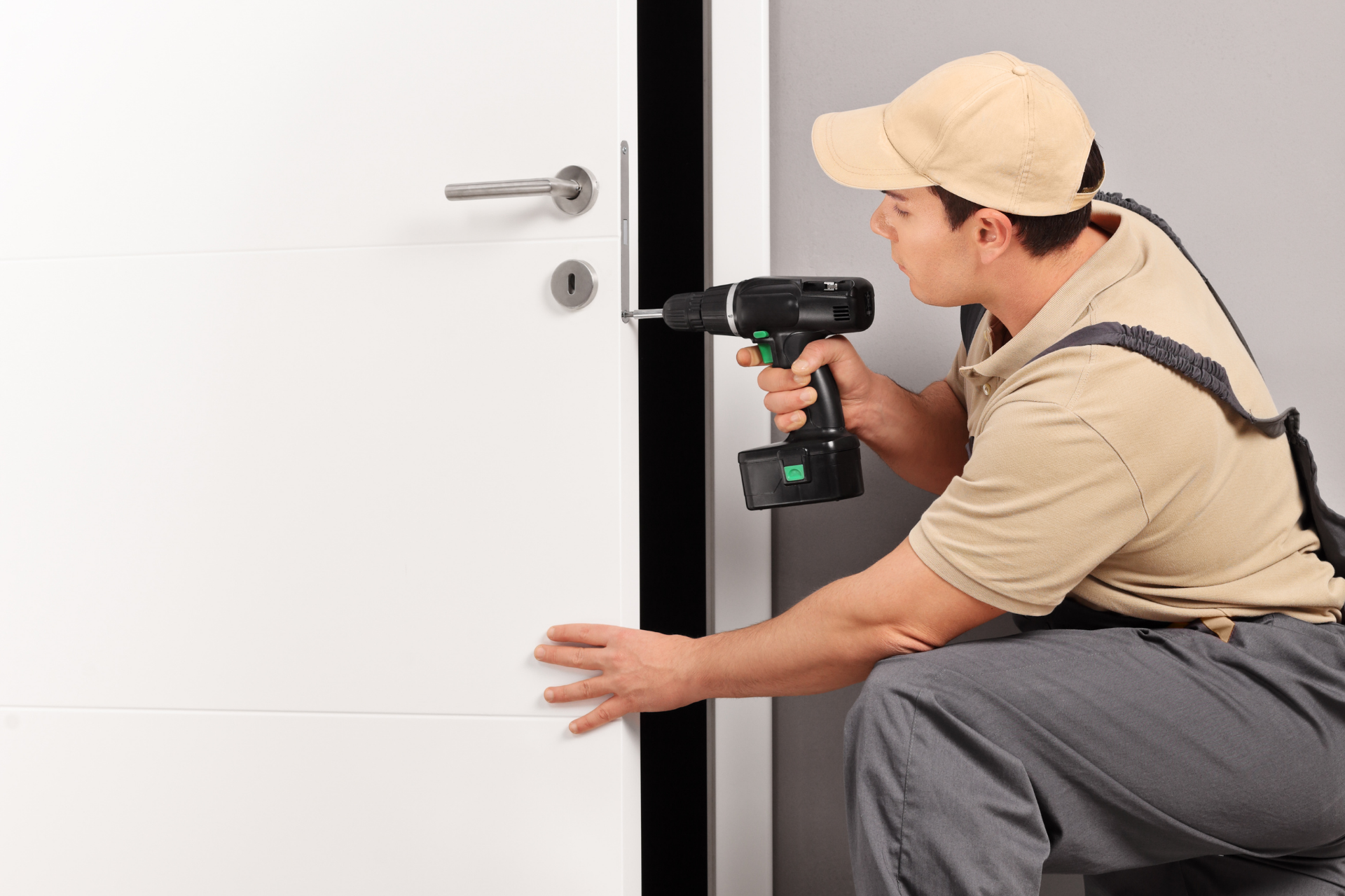 Handyman installing a door handle with a drill.