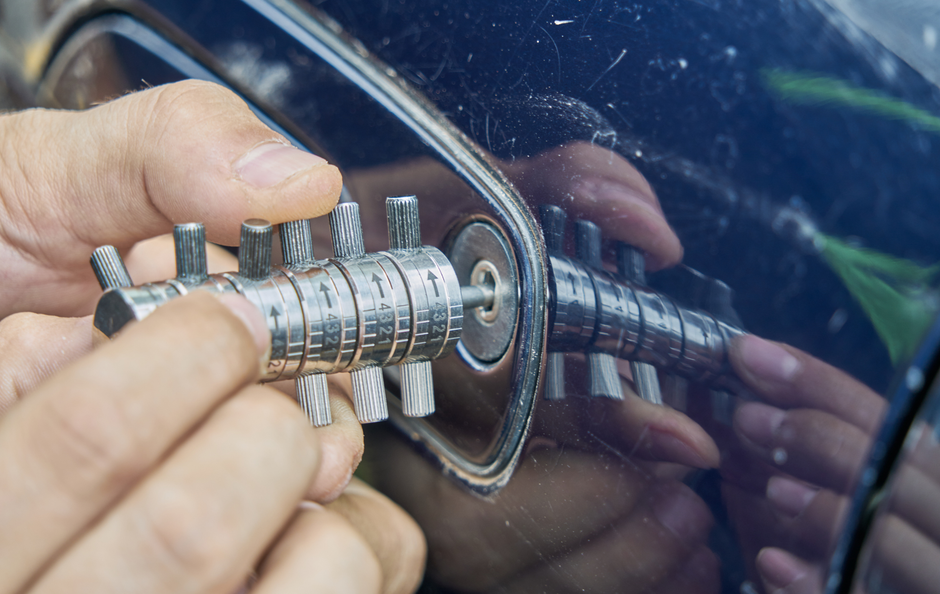Person using a lock pick to open a car door lock.