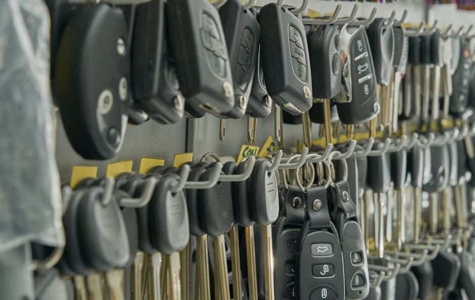 Keys hanging on hooks in a store, various car and house key types.