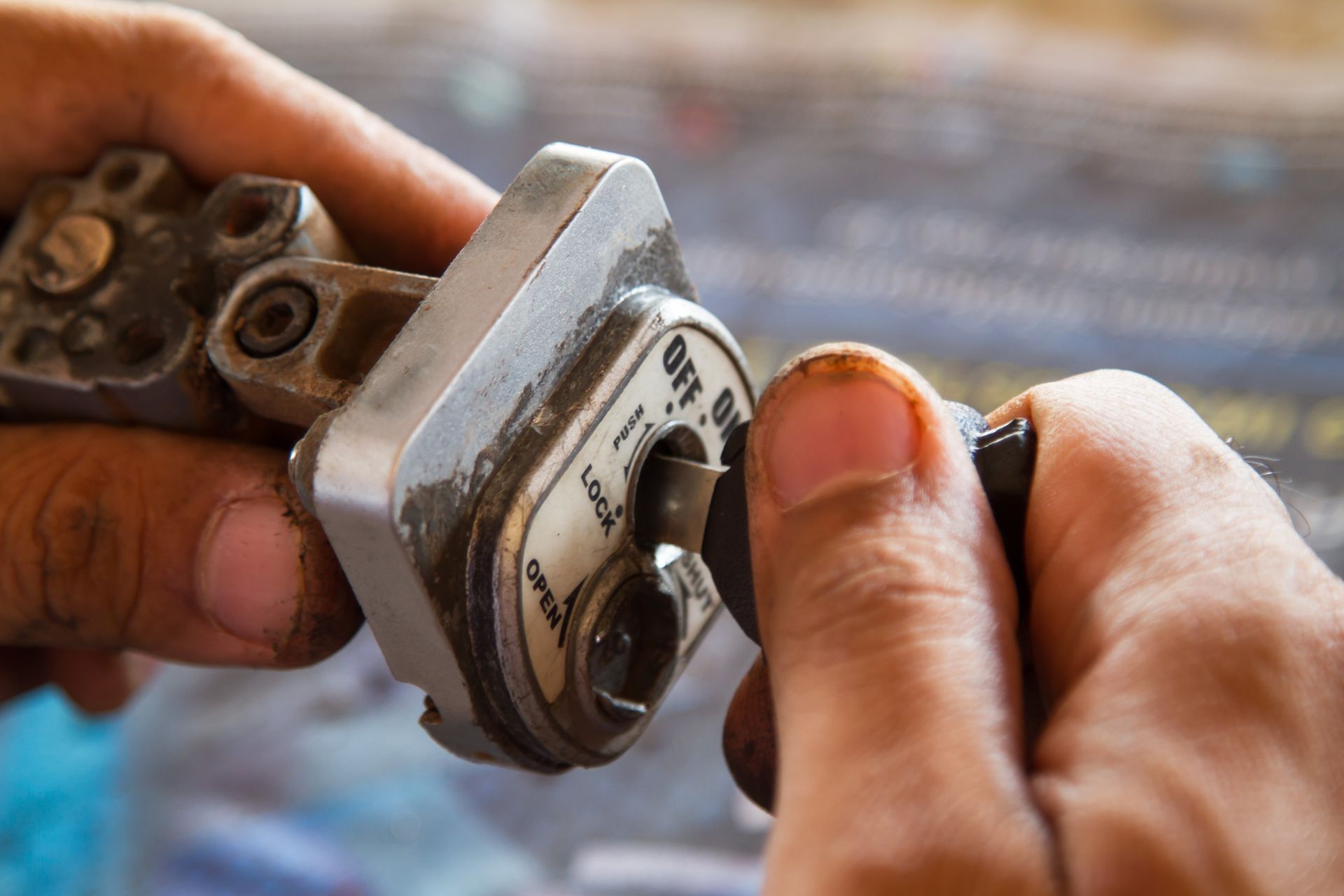 Hands turning a key in a metal ignition switch; settings labeled: Off, On, and Lock.