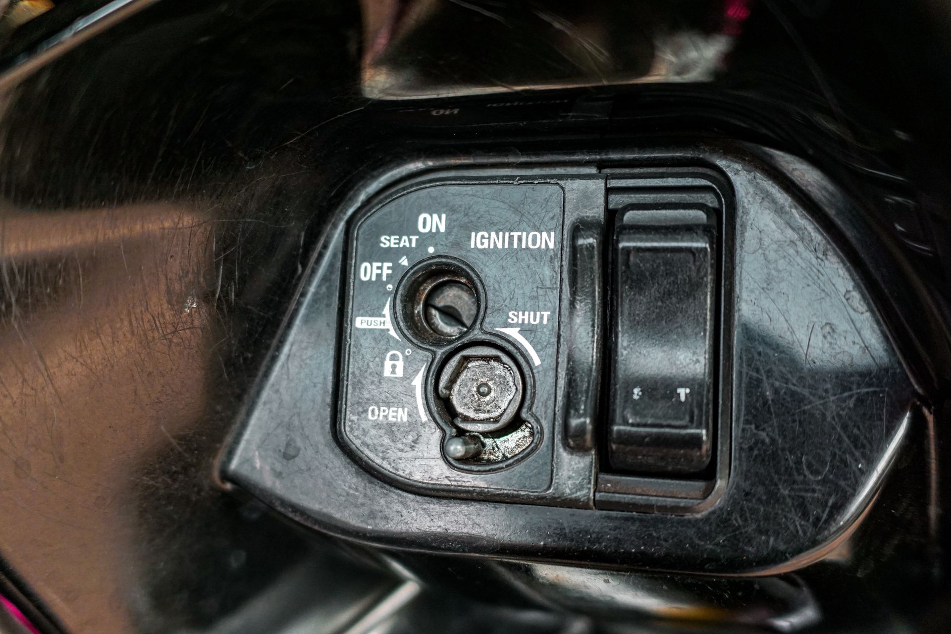 Black scooter ignition with key slot and on/off switch.