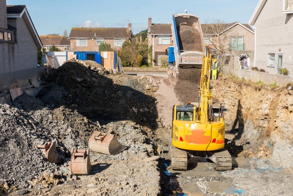 A yellow excavator is loading dirt into a dump truck at a construction site.