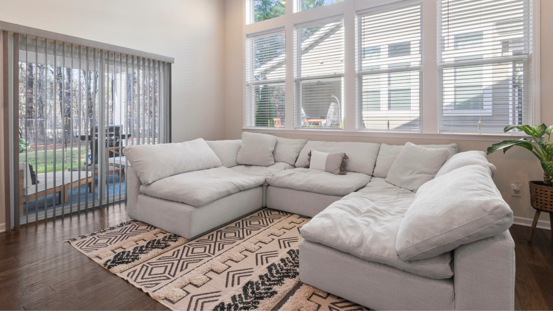 A living room with a large sectional couch and a rug.