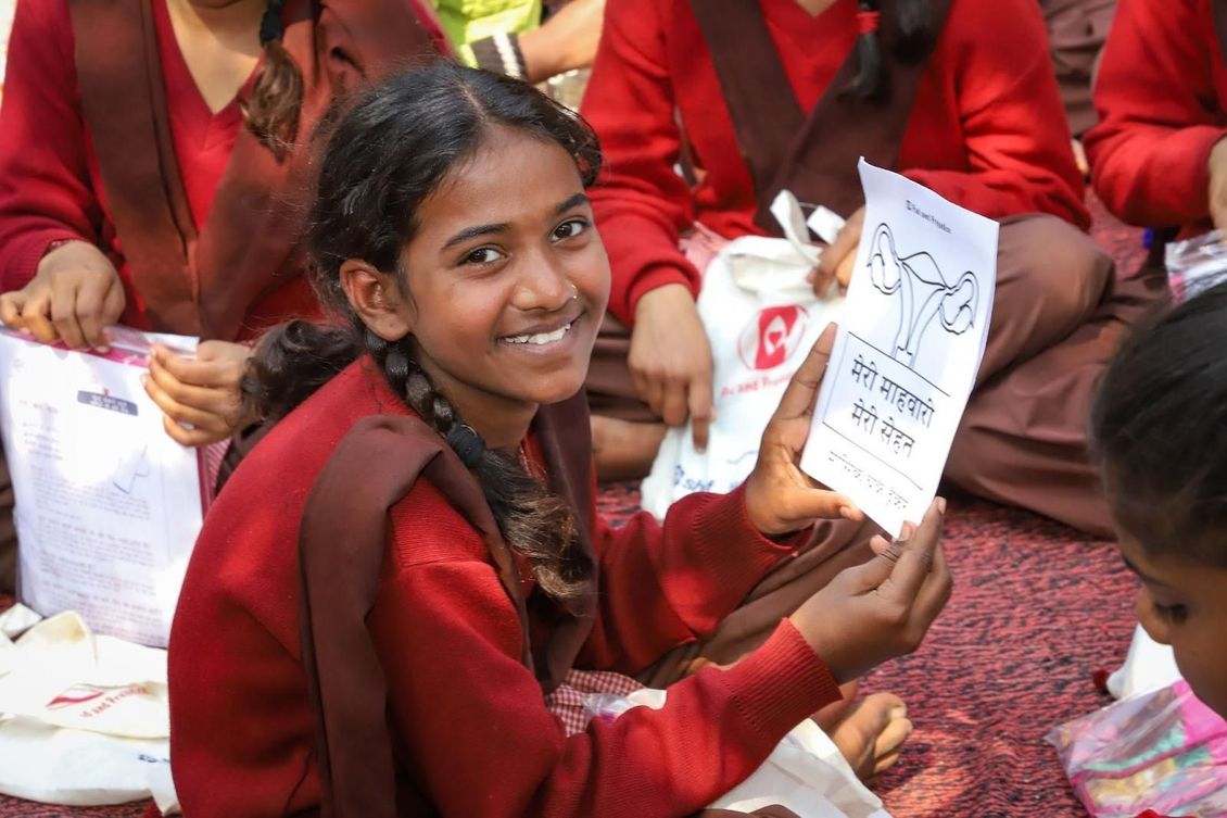 A girl is smiling while holding a piece of paper