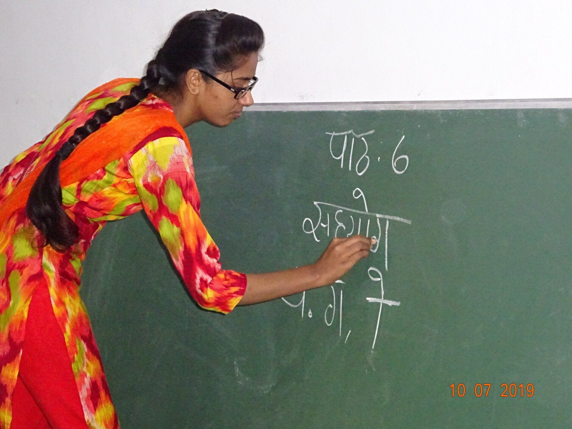 A woman is writing on a blackboard with chalk.