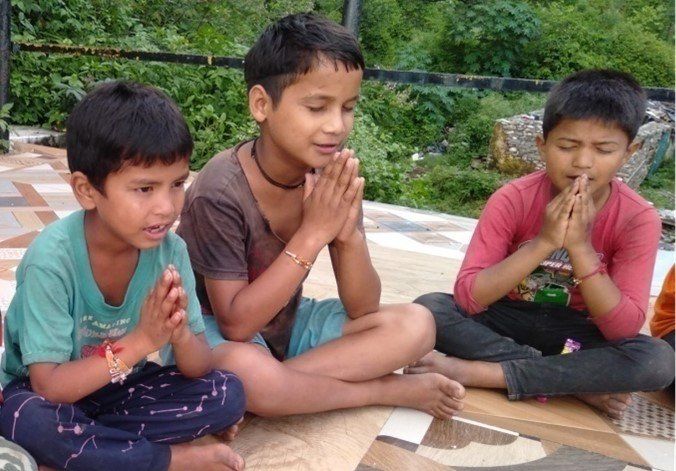 Three young boy students sitting together saying a prayer. 
