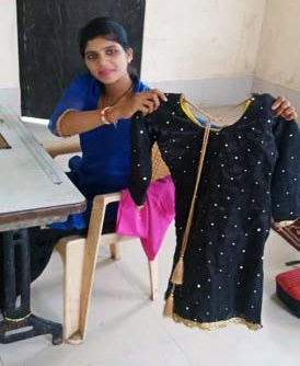 A woman is sitting in a chair holding a black dress.