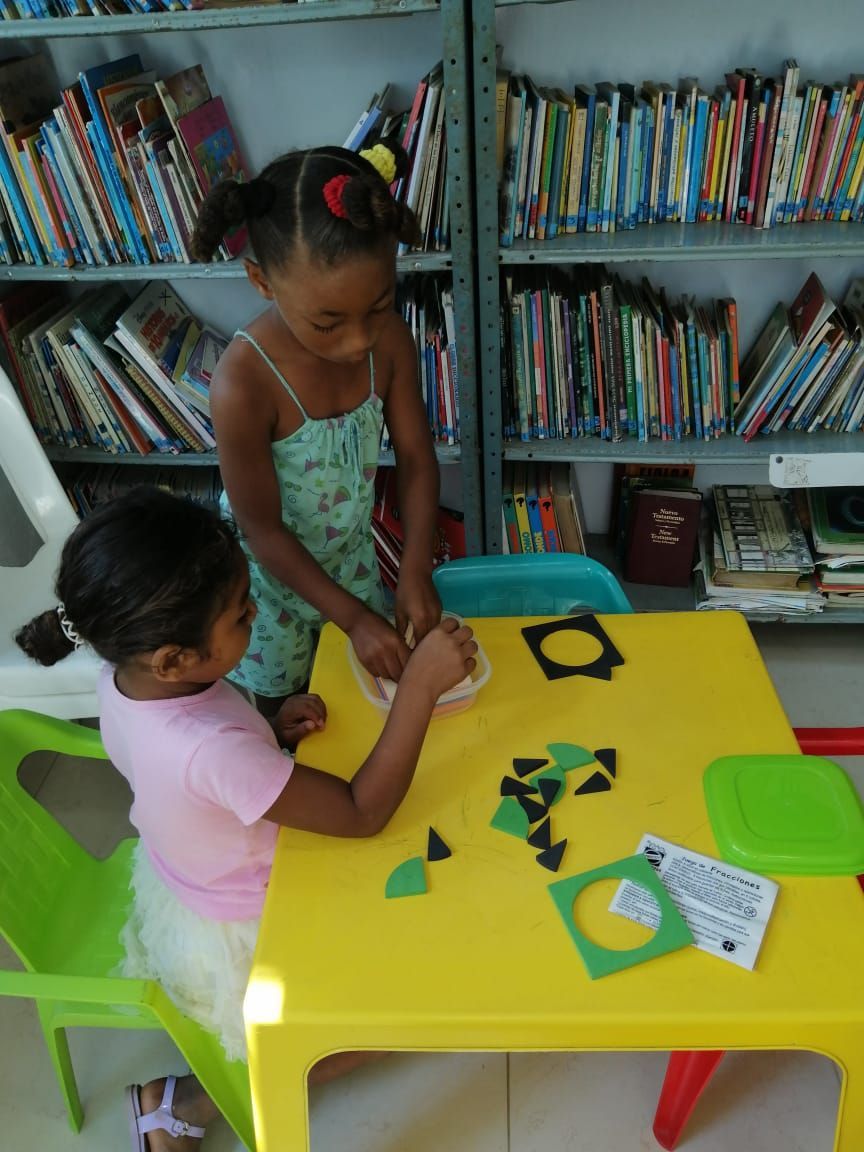 Two young students playing a counting game in the library. 