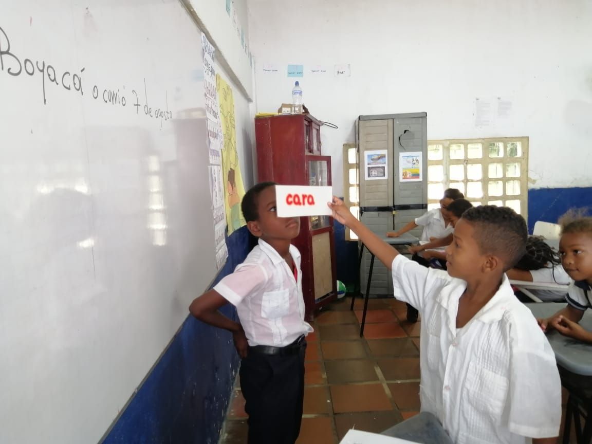 A young boy student holding up a card to another student that says 