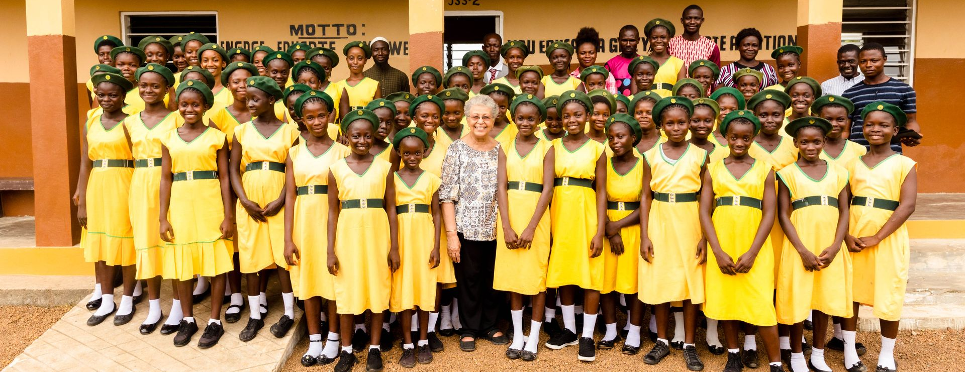 A group of children in yellow uniforms are posing for a picture