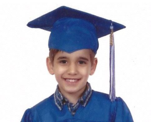 A young boy wearing a blue graduation cap and gown