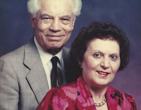 A man in a suit and tie stands next to a woman in a red dress