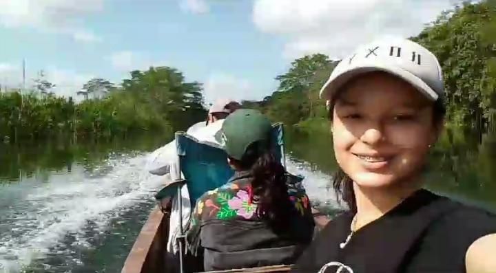 Girl taking a selfie riding a canoe on the river which is visible in the background