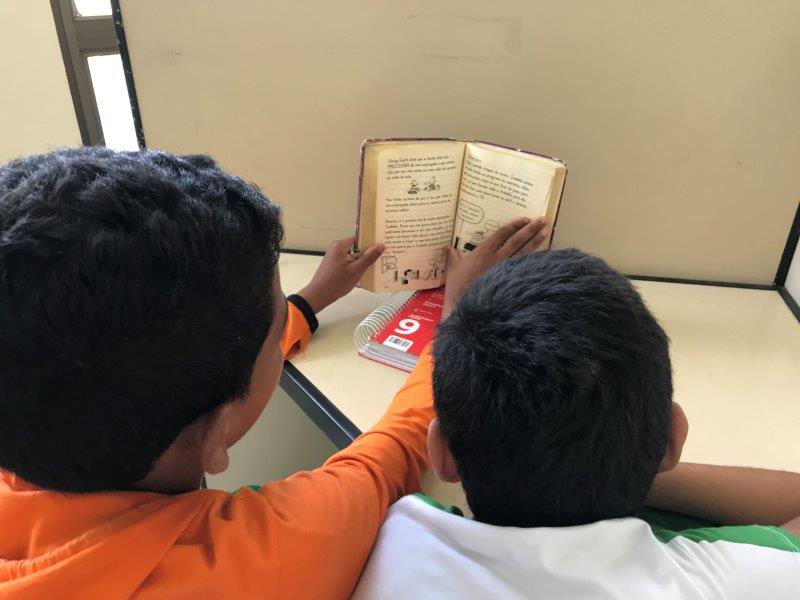 Two young students reading a book in their classroom at ADCAM. 