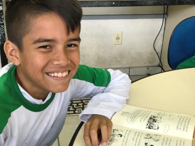 A young boy student smiling with his textbook.
