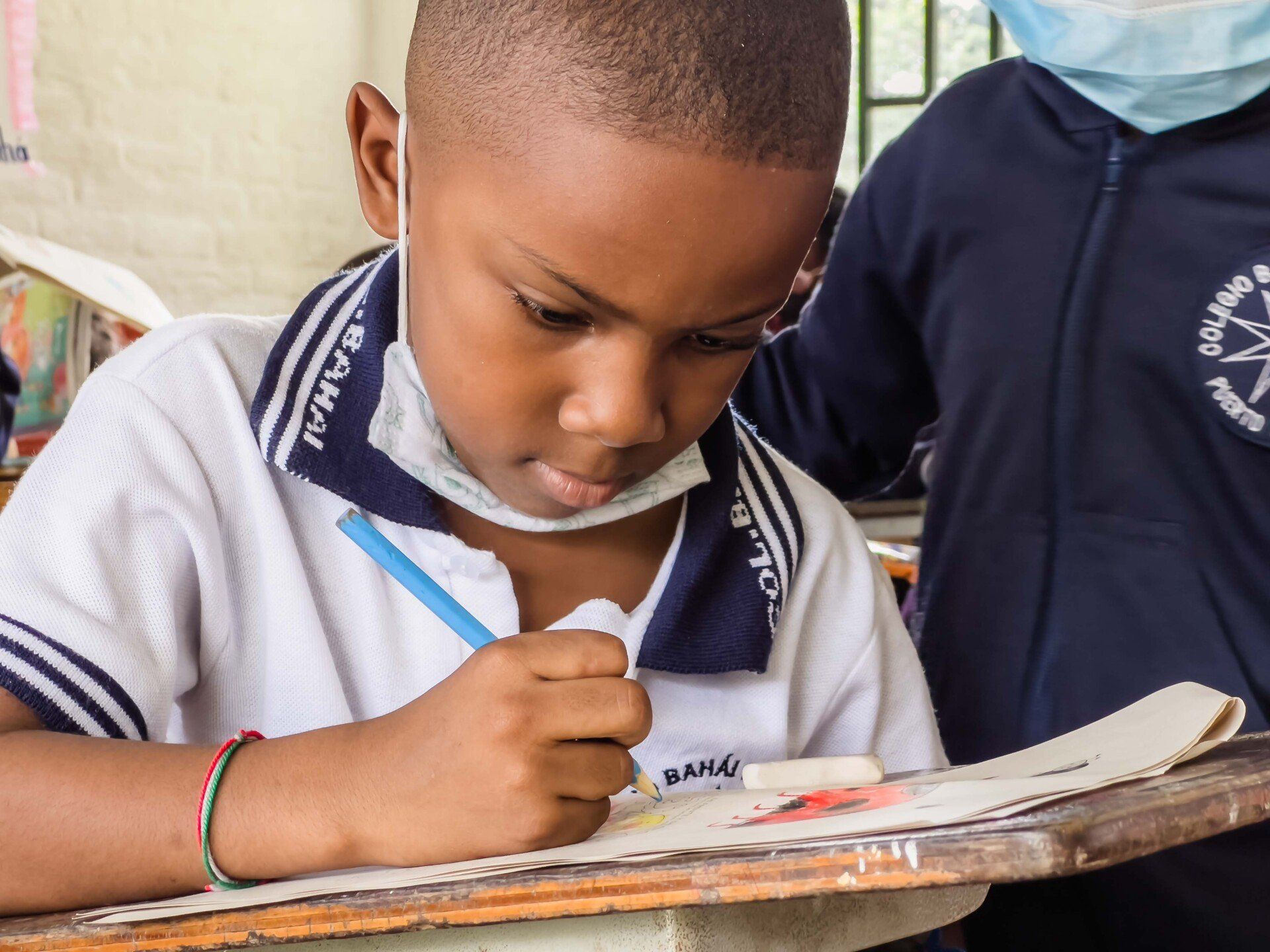 A young boy focused on writing at Ruhi Arbab Baha'i school, Colombia.