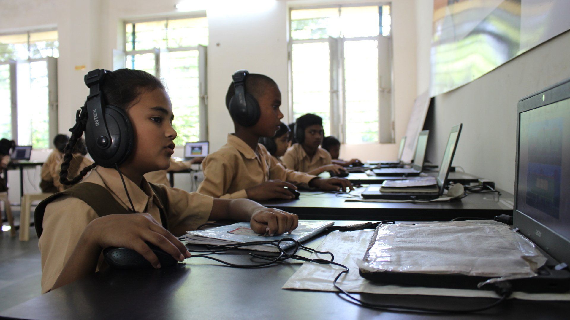 Young students working in the computer lab with headphones in. 