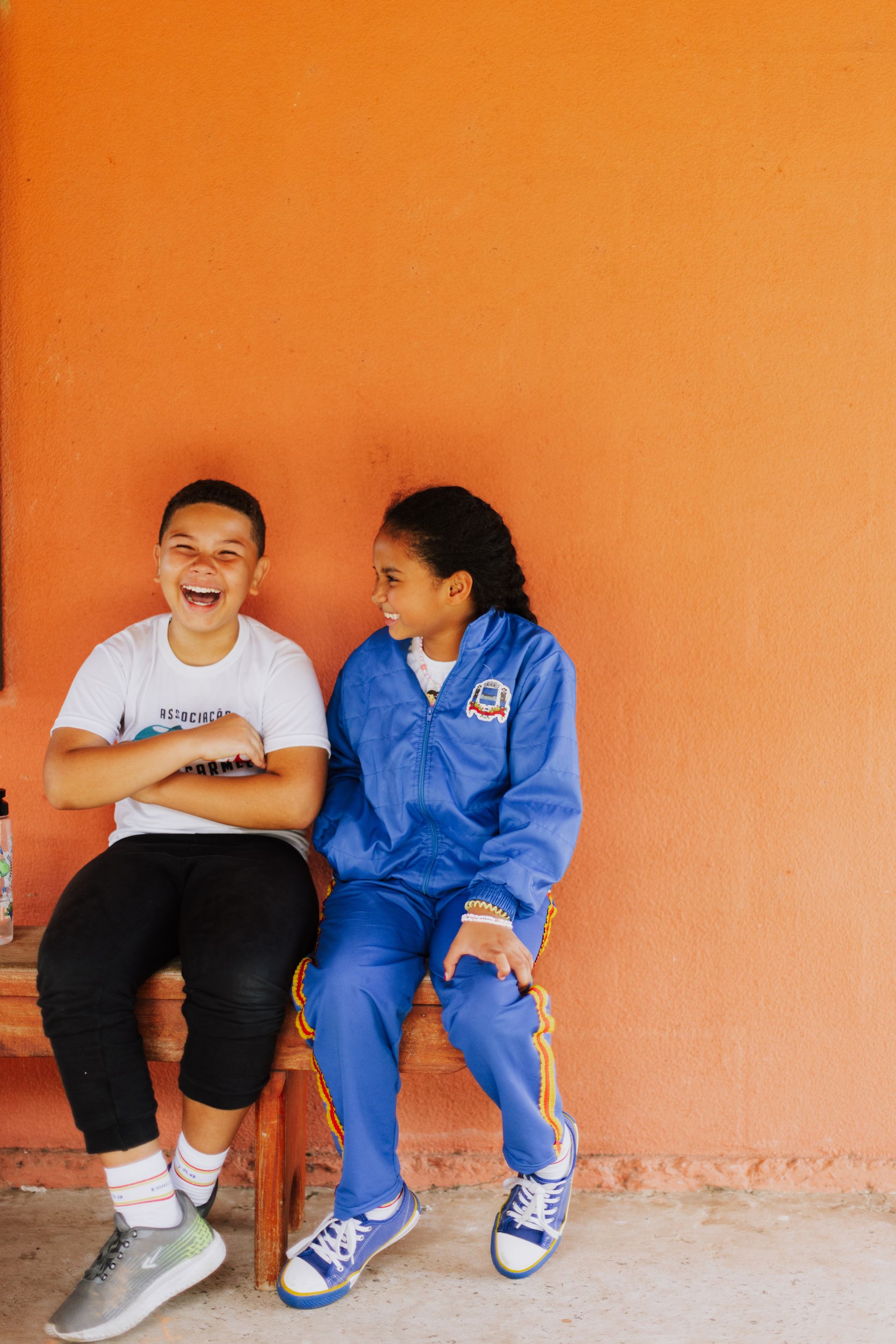 Two young students, a girl and a boy, smiling and laughing together. 