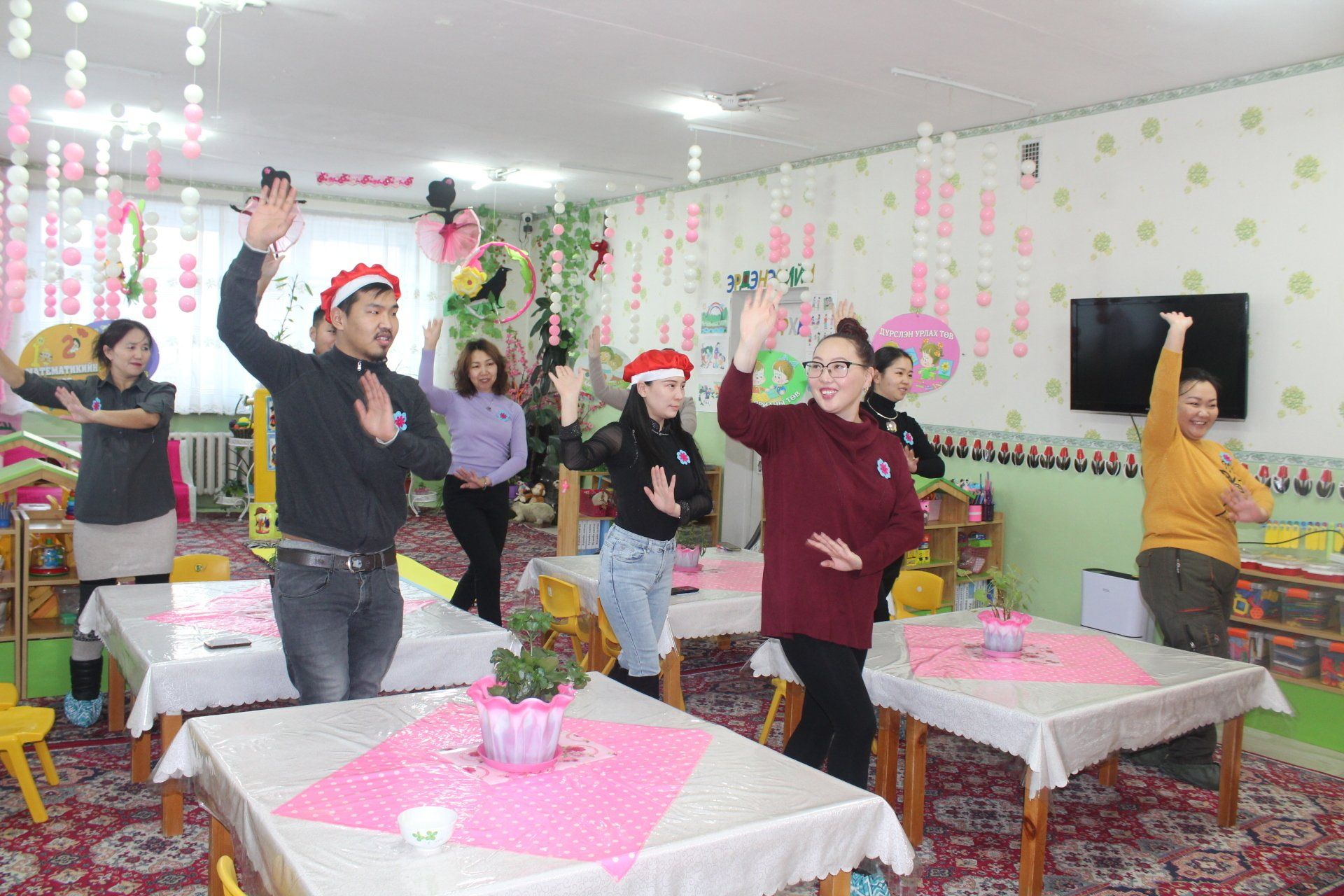 Parents participating in an interactive activity, all dancing with one hand up.
