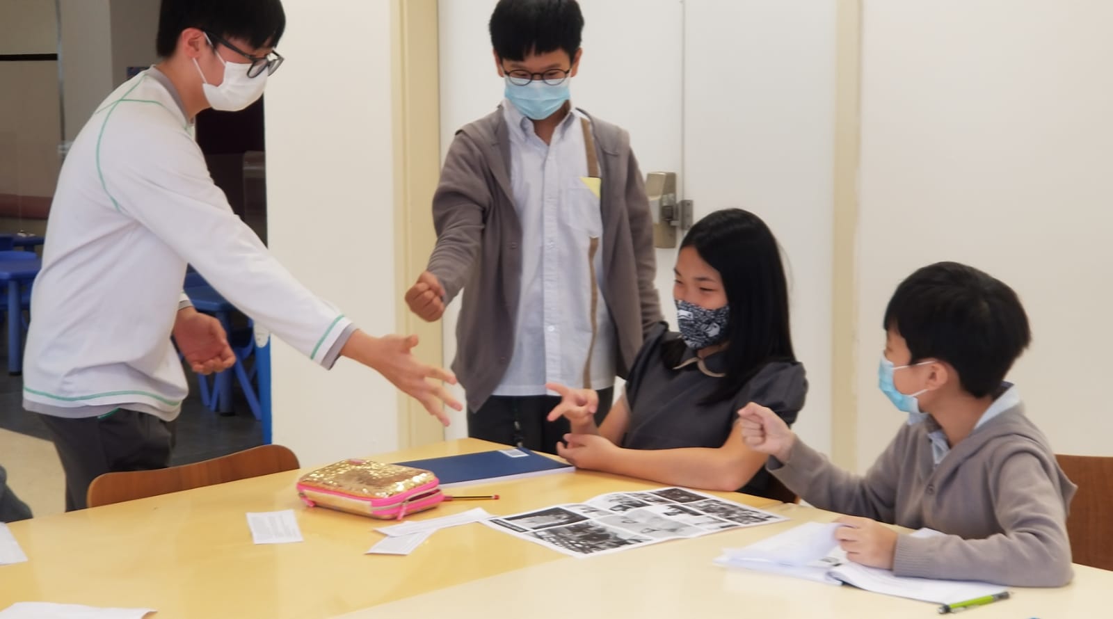 Four students playing 'Rock, Paper, Scissors' to delegate their project. 
