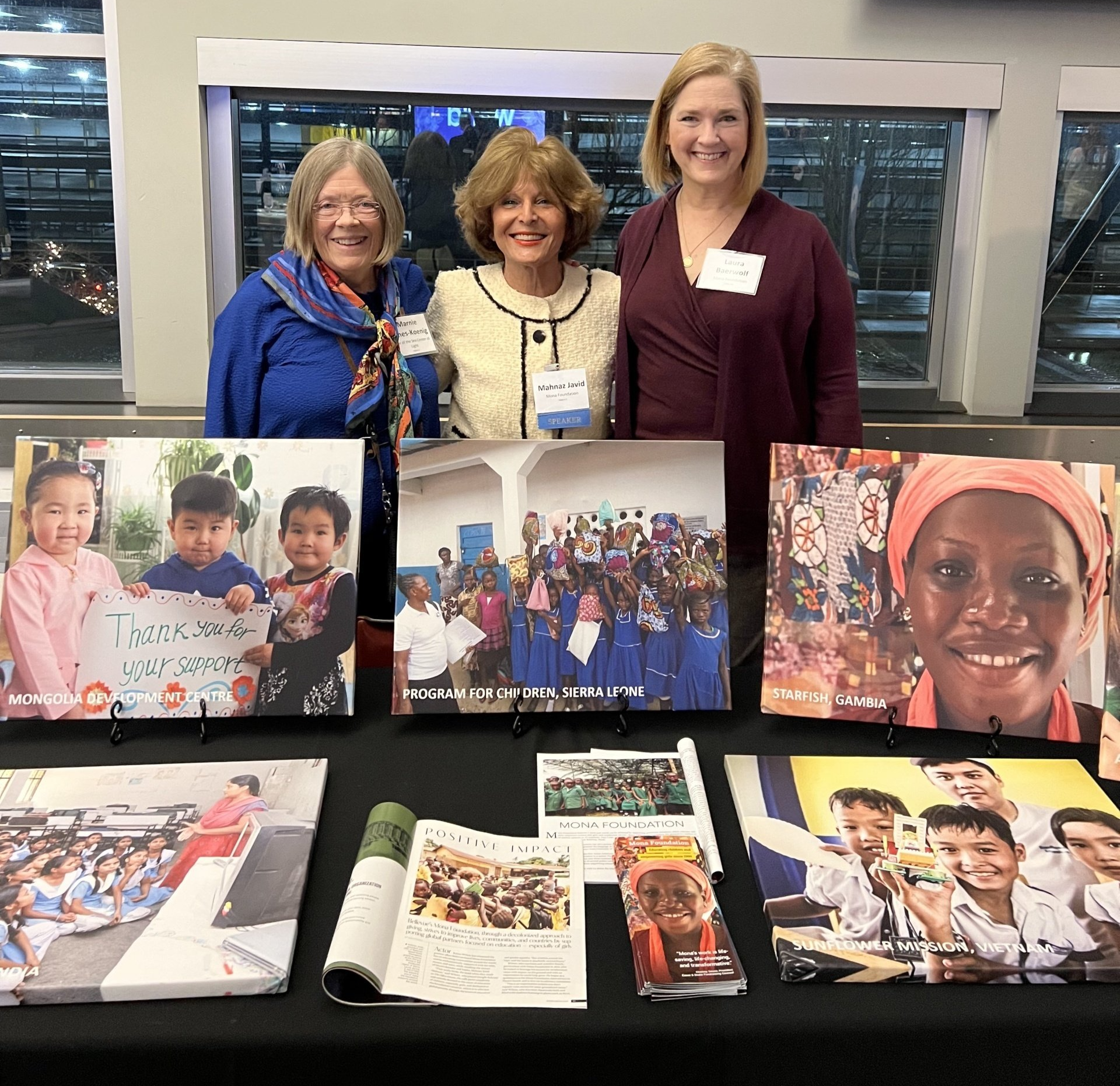 Three women standing in front of a table with pictures on it