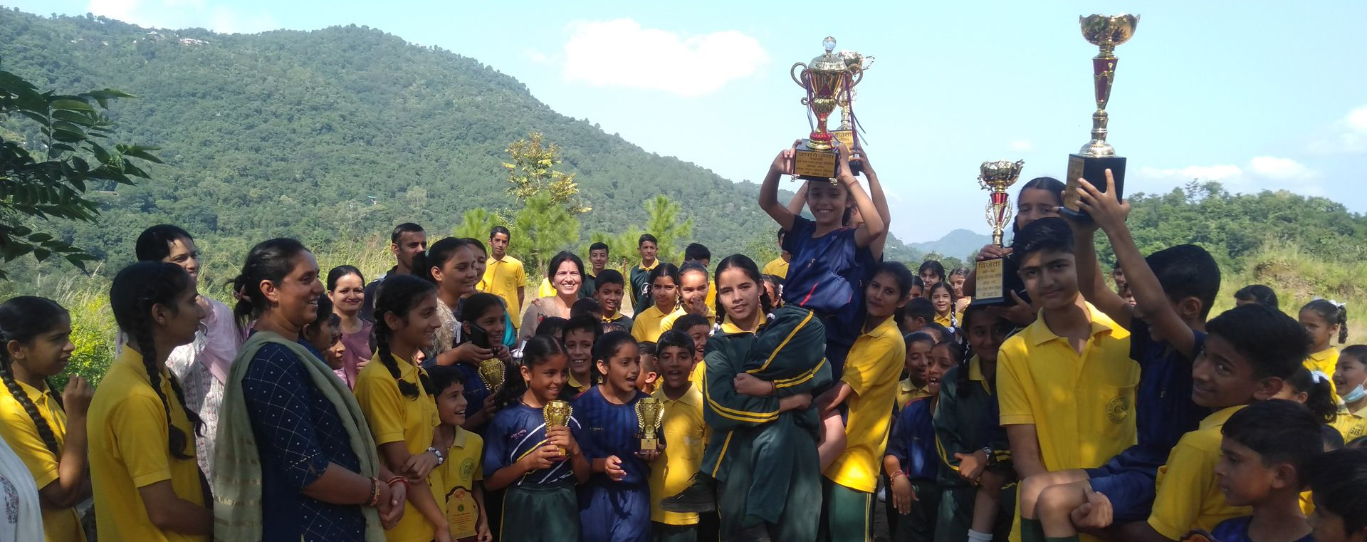 A group of children holding up trophies they just won in a sports tournament. 