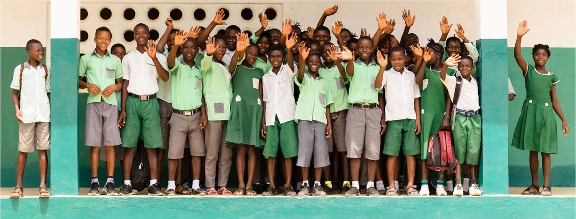 A group of children in green uniforms are posing for a picture