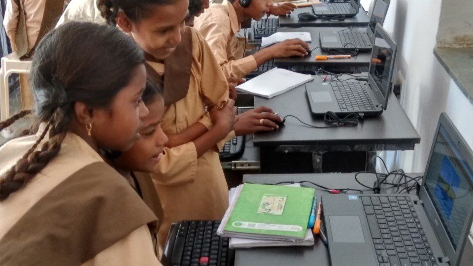 Two young girl students working on a  computer together. 
