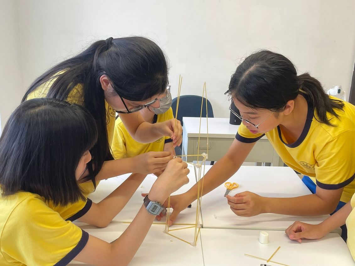 A group of young girls are sitting around a table working on a project.
