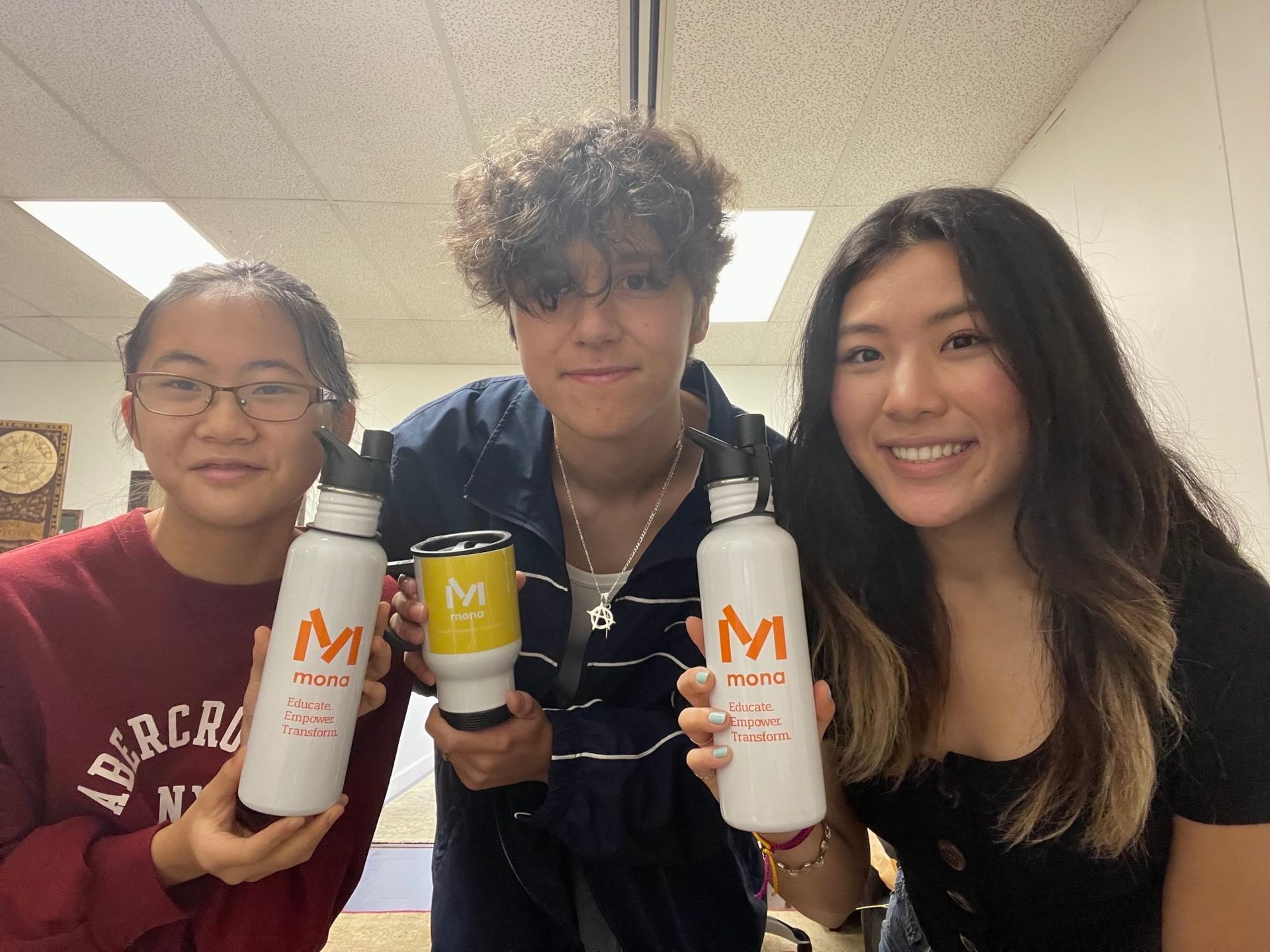 Three people are holding water bottles with the letter m on them.