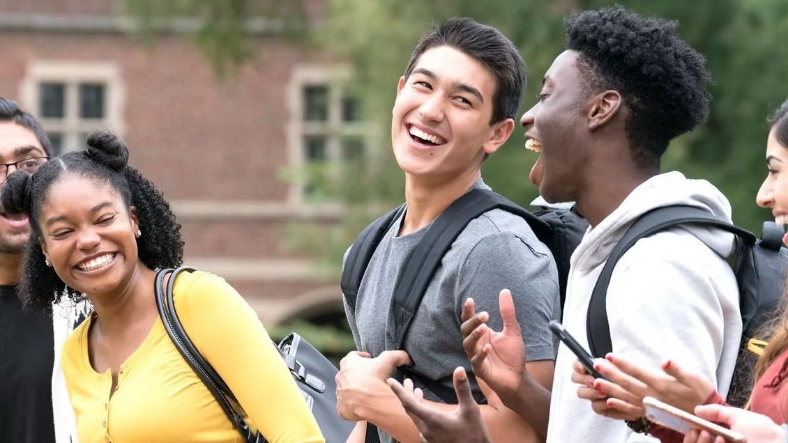 A group of young people are standing next to each other on a college campus.