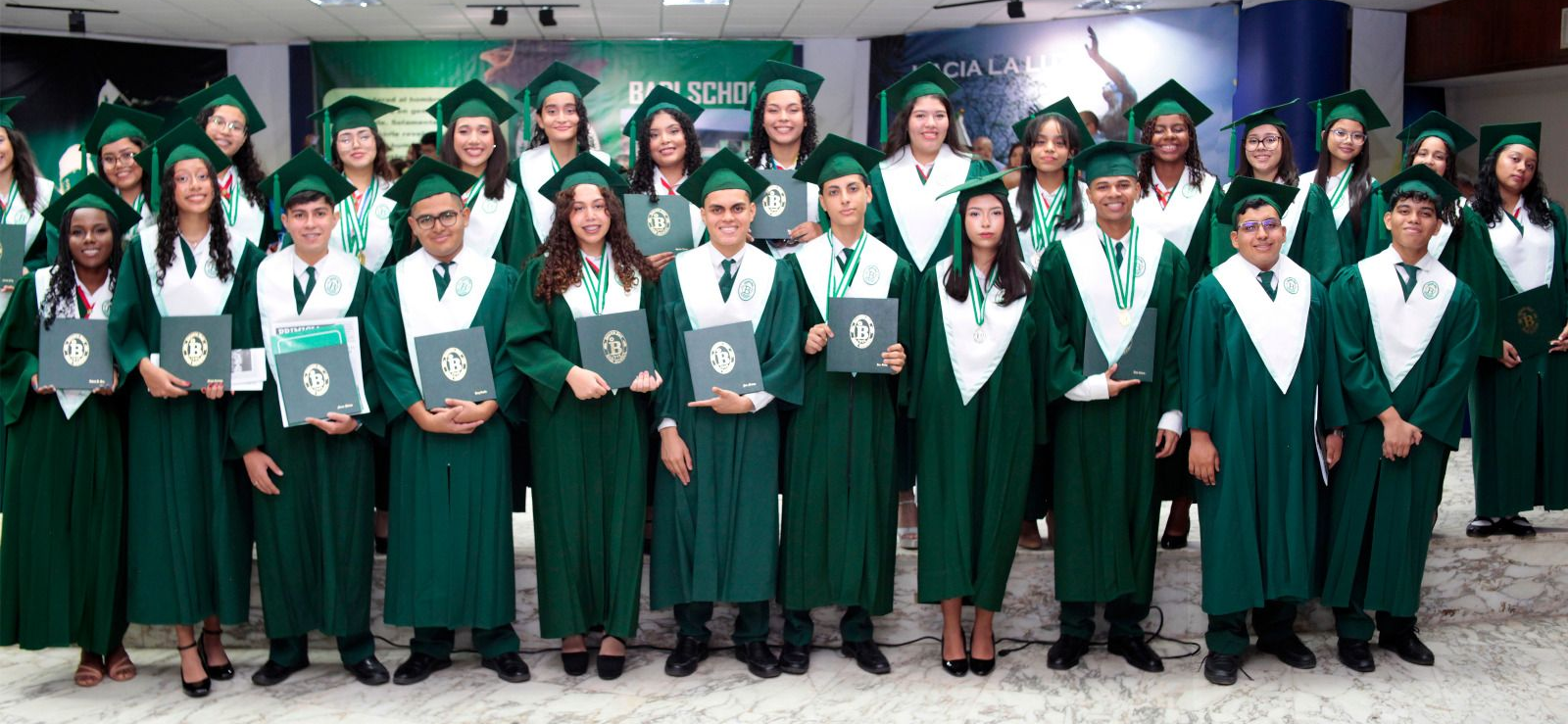 A group of young students in their graduation gowns holding their new high school diplomas.