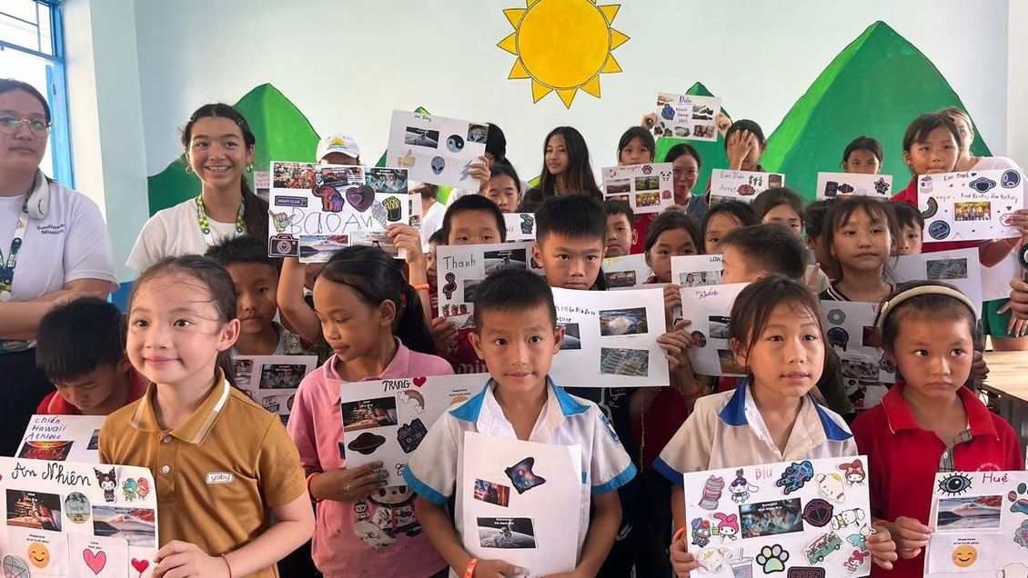 A group of children are holding up pictures in a classroom.