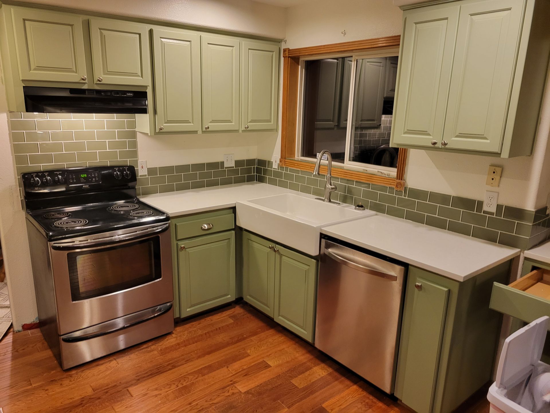A kitchen with green cabinets and stainless steel appliances