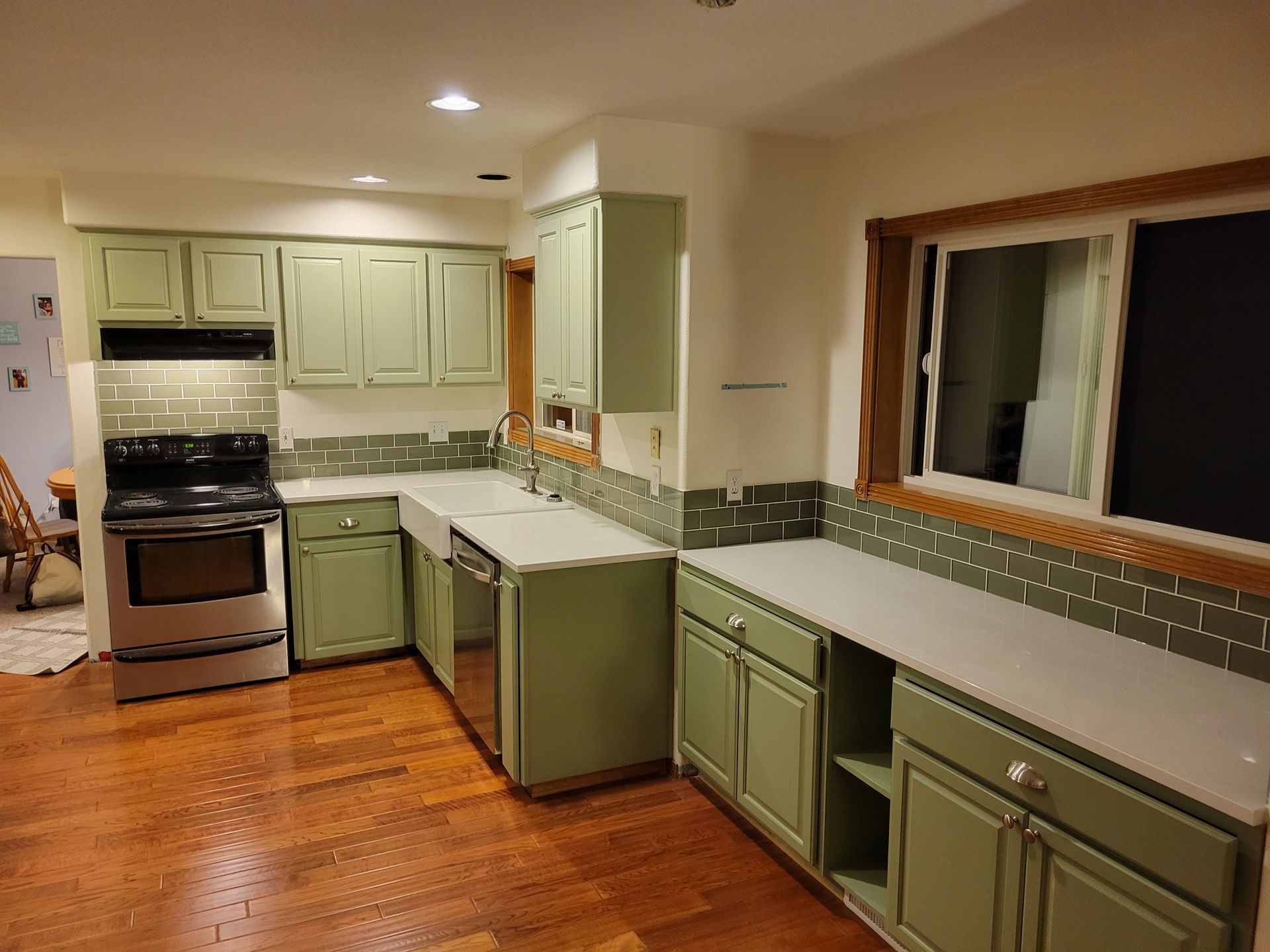 A kitchen with green cabinets and stainless steel appliances