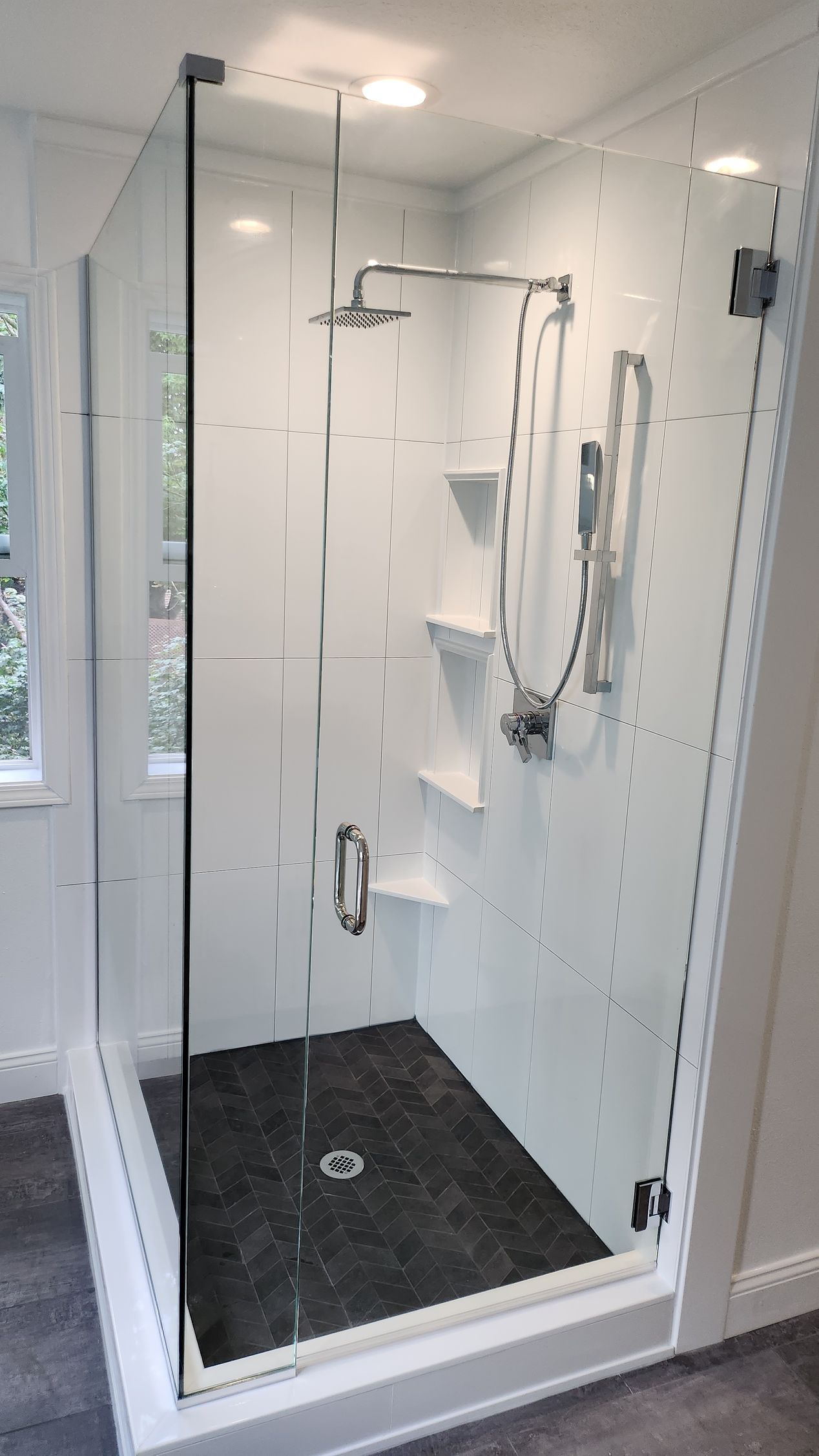 A bathroom with a walk in shower with a glass door.