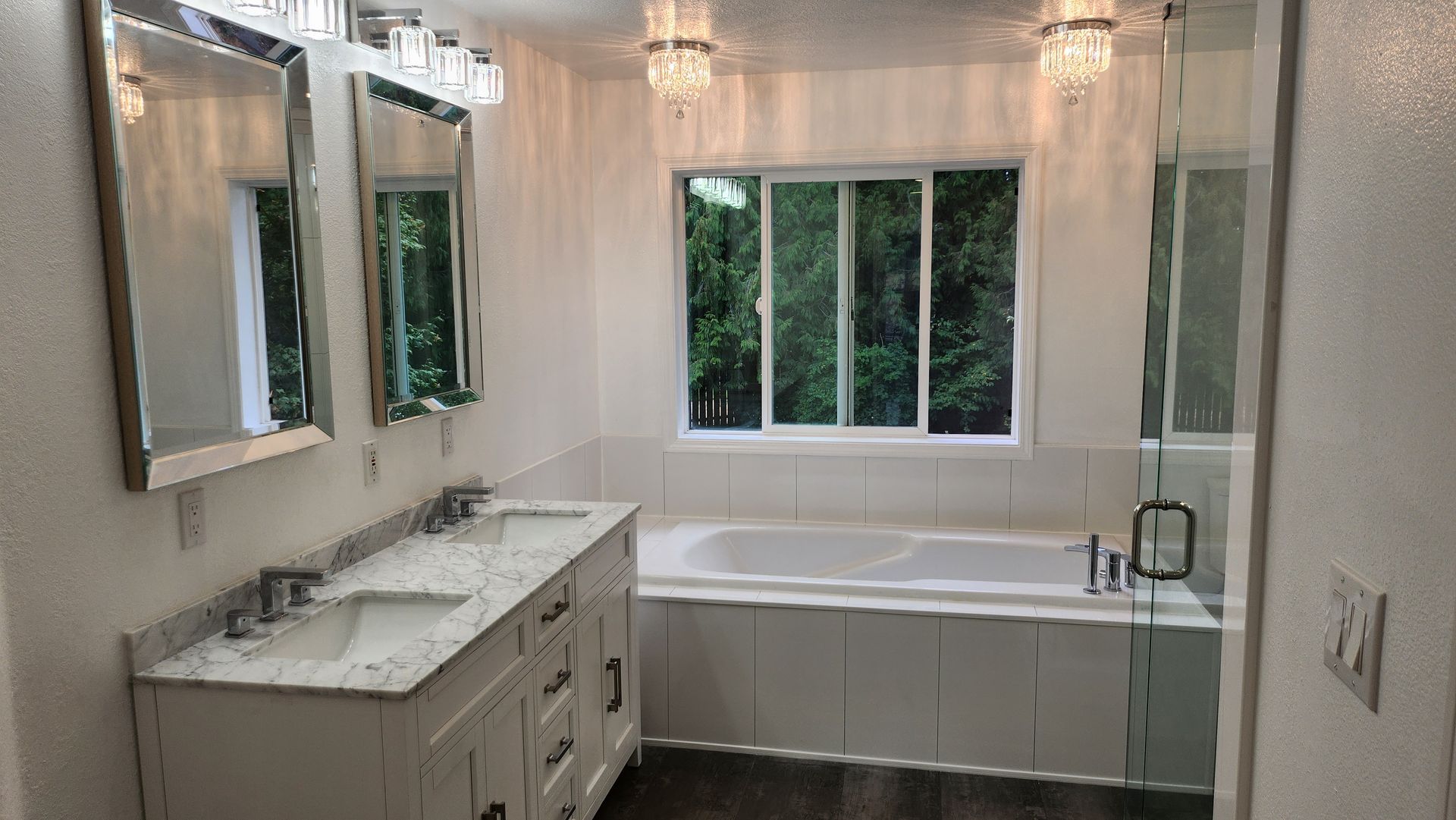 A bathroom with two sinks , a tub , and a window.