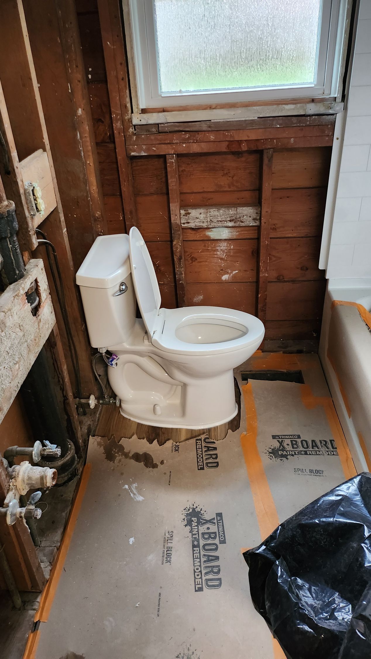 A toilet is sitting in a bathroom under construction.