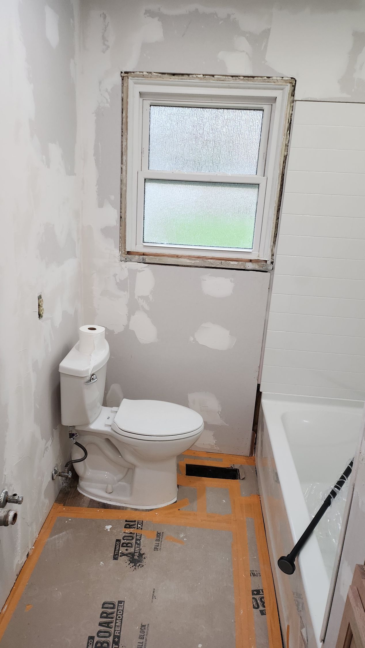 A bathroom with a toilet , tub and window.